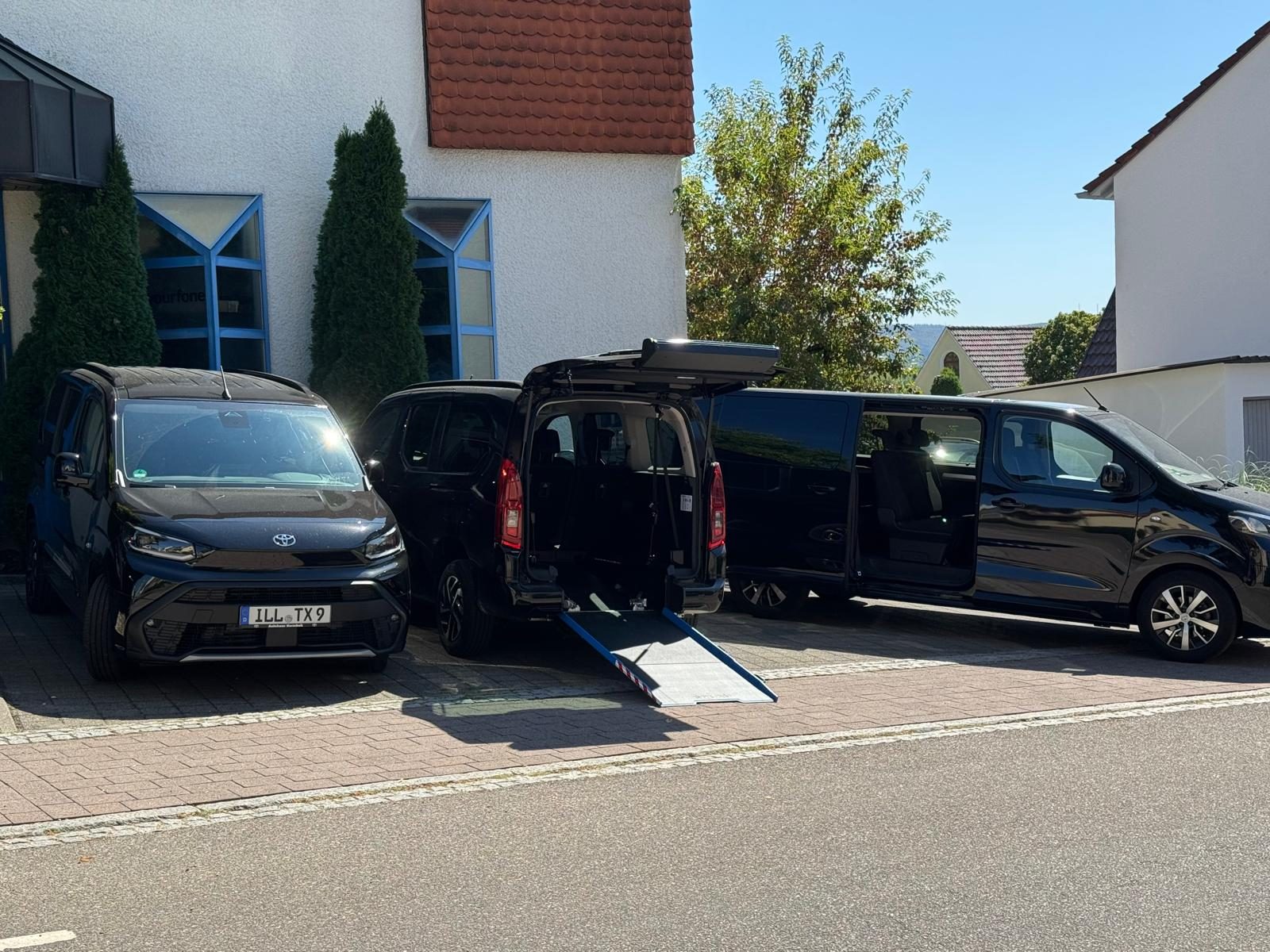 Drei schwarze Fahrzeuge von minicar-gp nebeneinander in Göppingen – in der Mitte ein Toyota Proace City mit ausgeklappter Rollstuhlrampe, rechts der Großraumvan mit offener Schiebetür